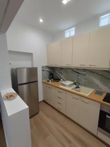 SelíniaSelinia Residence的厨房配有白色橱柜和不锈钢冰箱