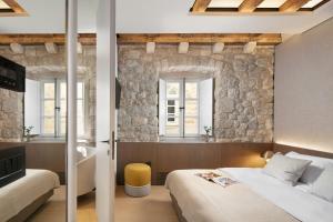 杜布罗夫尼克Villa Lapisa的一间卧室设有两张床和石墙