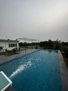 TibriLuxury Farmhouse Stay, Pure Vegetarian- Santushti Farm, NCR的庭院里的一个蓝色海水游泳池