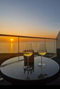 纽基Sea View Apartment at One Lusty Glaze的两杯酒杯坐在桌子上,背面是日落