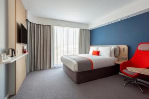 迪温特Holiday Inn Express & Suites - Deventer, an IHG Hotel的酒店客房,配有一张床和一张红色椅子