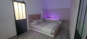 托莱多El susurro del tajo La gruta的一间卧室配有一张床和一个紫色光水槽