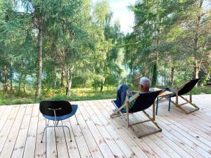 BrzozieLunette Lodge am See mit Sauna für 10 Gäste的坐在木甲板上椅子上的男人