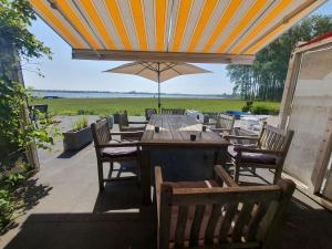 坎珀兰Cosy holiday home on Lake Veere with the beach right at your doorstep的庭院内桌椅和遮阳伞