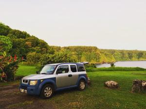 Ah Fong VillageGo Camp Maui的停在田野上的蓝色和银色吉普车