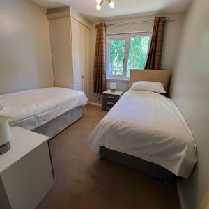 阿维莫尔Aviemore Bungalow, Dalfaber的一间卧室设有两张床和窗户。