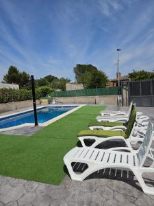 托莱多Chalet con piscina en escalona的游泳池旁的一排白色躺椅