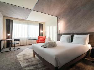 鹿特丹鹿特丹布莱恩诺富特酒店的酒店客房设有一张大床和一张红色椅子。
