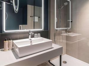 鹿特丹鹿特丹布莱恩诺富特酒店的浴室配有白色水槽和淋浴。