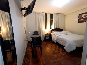 卡哈马卡Hotel la encantada的一间卧室配有一张床、一张书桌和一台电视