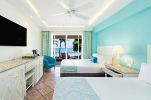 塔马林多Hotel Tamarindo Diria Beach Resort的酒店客房设有两张床和一台平面电视。