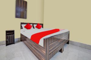 贾姆谢德布尔OYO Flagship Prakash Inn的一间卧室配有一张带红色枕头的木床。