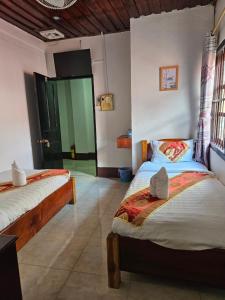 琅勃拉邦Chitlatda Bila House的一间卧室设有两张床,另一间房间设有一扇门