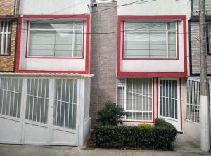 波哥大Alojamiento "Cómo en CASA" cerca al Aeropuerto!!的白色门和红色装饰的房子