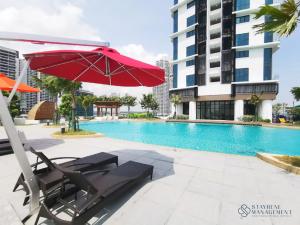 努沙再也Almas Suites Puteri Harbour by Stayrene的游泳池旁的红色遮阳伞和椅子