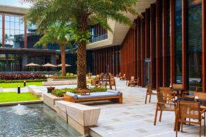 海口海口万丽酒店 的一间设有桌椅的餐厅,种植了棕榈树