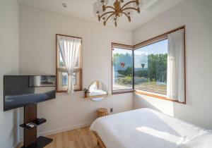 江陵市Dignitas Luxury Villa的一间卧室设有一张床和一个大窗户