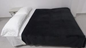 塔里哈Apartamento Privado SOL的一张带白色床单和黑色毯子的床