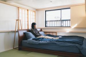 Taketa竹田まちホテル的坐在窗户房间里床边的女人