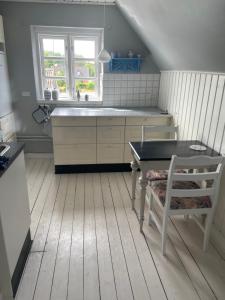 古兹耶姆ØsterLars blue Pearl的厨房配有水槽、桌子和椅子