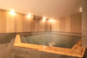 札幌QuintessaHotel SapporoSusukino63 Relax&Spa的木墙客房的按摩浴缸