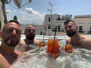 加利波利B&B Salentus的三个男人在游泳池里喝着饮料