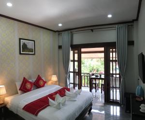 琅勃拉邦Le KhounSok Boutique Hotel的一间带大床的卧室和一个阳台