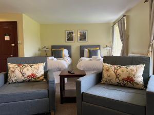 阿尔斯通Lovelady Shield Country House Hotel的一间设有两张床、一张沙发和一把椅子的房间