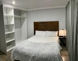 比勒陀利亚Jan Bantjies Inn的一间卧室配有一张带木制床头板和架子的床。
