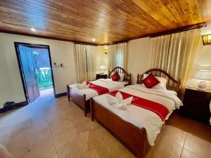 琅勃拉邦Villa Phathana Royal View Hotel的一间卧室配有两张带红色枕头的床