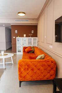 内坦亚Стильные апартаменты Dotan的一张橙色沙发,位于带桌子的房间