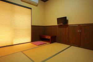 指宿市Family Ryokan Kawakyu with Showa Retro, private hot spring的客房设有电视、桌子和窗户。