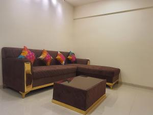 孟买OSI Apartments Santacruz的客厅配有带色彩缤纷枕头的棕色沙发