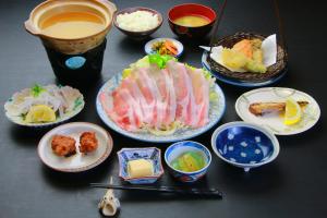 指宿市Family Ryokan Kawakyu with Showa Retro, private hot spring的餐桌,盘子上放着食物和碗