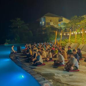 枚州县BAKHAN VIEWEST GLAMPING的一群人晚上坐在游泳池周围