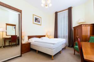 卡罗维发利Spa Hotel Anglický Dvůr的一间卧室配有一张床、镜子和一张桌子