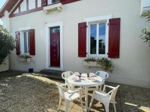 卡布勒通Appartement cosy avec terrasse, jardin et parking à 200m de la plage - FR-1-413-111的白色房子前面的白色桌子和椅子