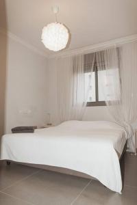内坦亚Стильные апартаменты Dotan的白色的卧室设有白色的床和窗户。