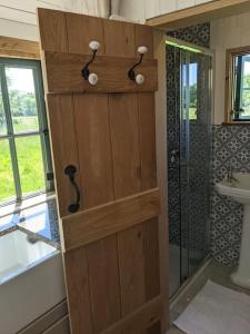CowfoldKenny’s Hut的浴室设有木制门,配有淋浴