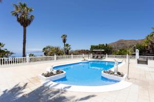 阿坎提拉德洛斯基拉斯弗洛雷斯别墅酒店的一个带棕榈树和围栏的游泳池