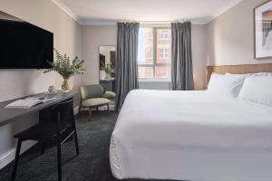 珀斯Pensione Hotel Perth的酒店客房设有一张大床和一张书桌。