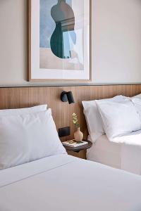 珀斯Pensione Hotel Perth的两张带白色床单的床和一张墙上的照片