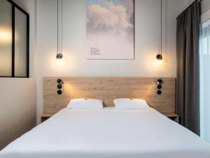那慕尔ibis Styles Namur的卧室配有一张带两个枕头的大白色床