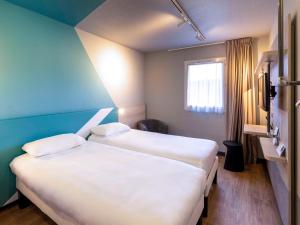 米洛ibis Budget Millau Viaduc的客房设有两张床和窗户。