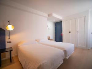 卡尼略洛克梅勒酒店的白色卧室配有一张大床和一张桌子