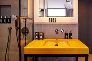 乌尔姆me and all hotel Ulm, part of JdV by Hyatt的浴室设有黄色水槽和淋浴