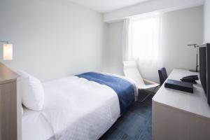 釜石福尔克罗三里库酒店的一间卧室配有一张床和一张书桌及电视
