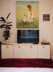 卡尔派尼西翁Το Σπίτι Της Ευτυχίας στούντιο的一间配有电视的房间,墙上挂有绘画作品