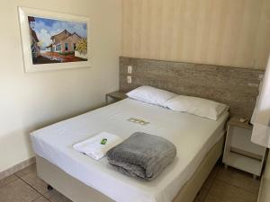 戈亚尼亚Pissin Plaza Hotel的卧室配有白色的床和毛巾