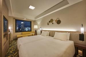 神户The Royal Park Canvas - Kobe Sannomiya的酒店客房设有两张床和窗户。